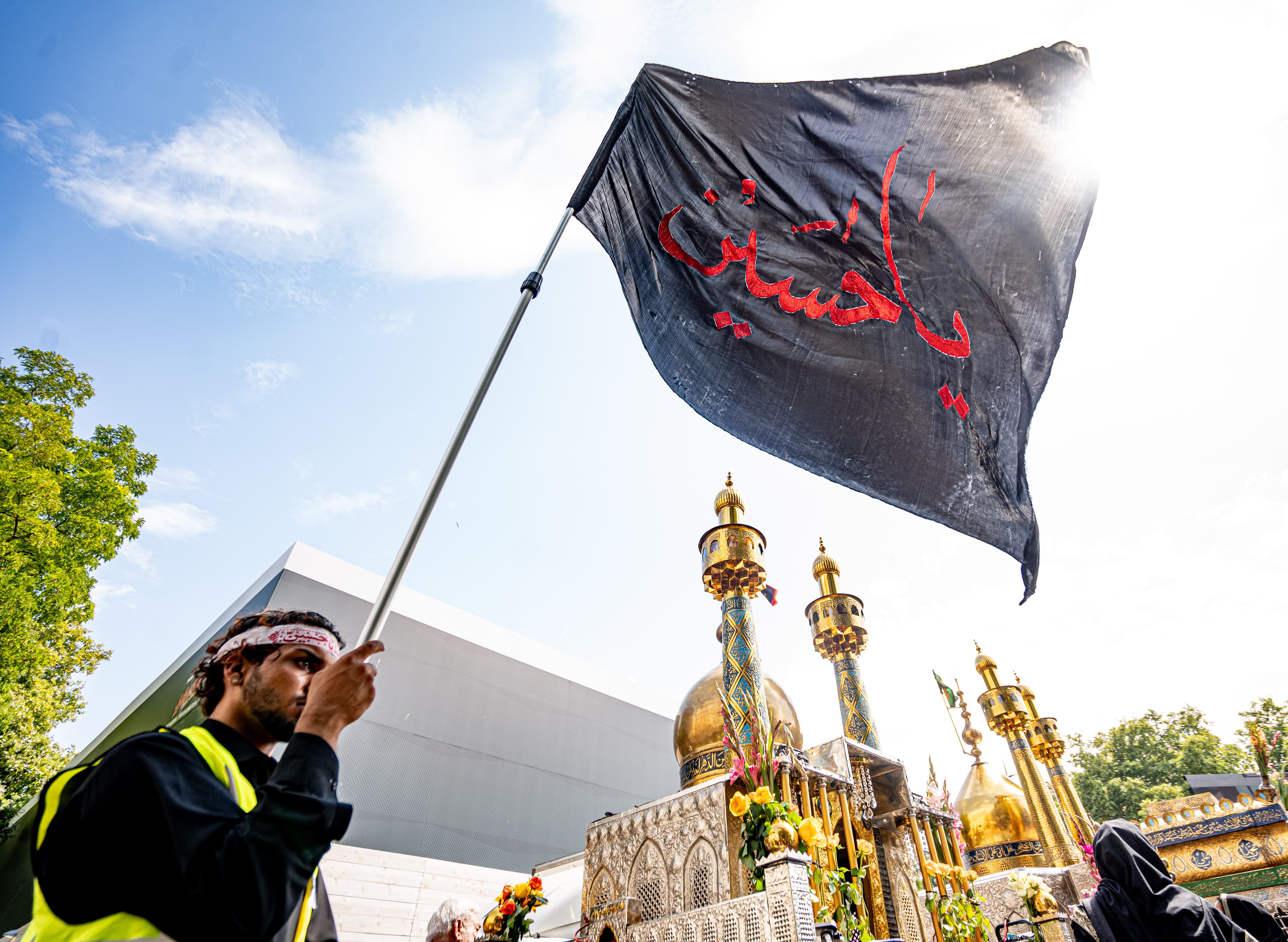 A black remembrance flag raised beside the procession.